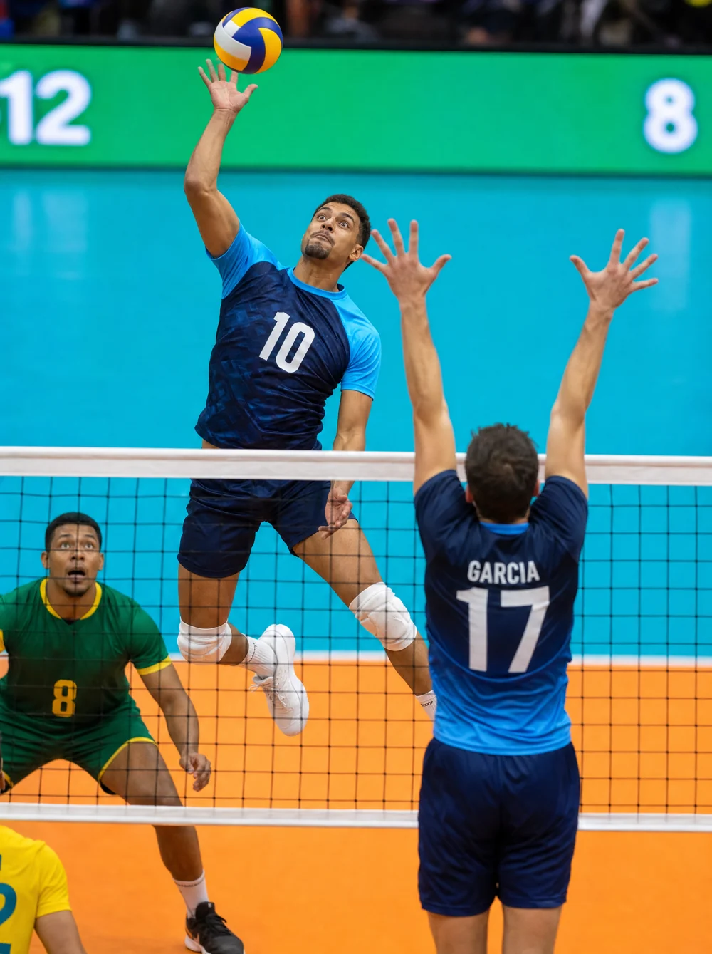 Atleta de vôlei de quadra em ação de ataque no ar sobre a rede com uniforme personalizado